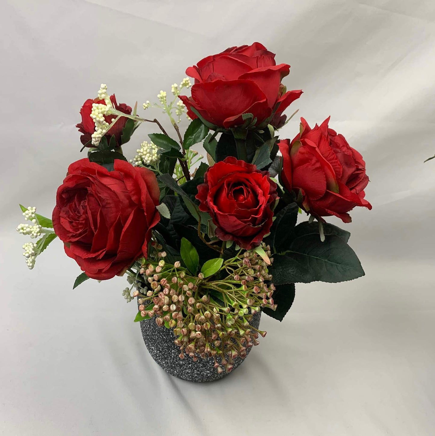 Gorgeous artificial flower arrangement of beautiful crimson artificial cabbage roses and partially bloomed Somerset roses, presented in a speckled ceramic vase with a black and white design. Dimensions: 31cm in height and 35cm in width. Atelier Blooms Auc