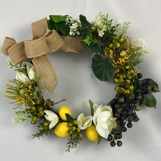 Our Lemon Wreath is a fresh take on the traditional and offers bright sunny lemons with white flowers and black and green berries with white peonies and yellow spider chrysanthemums, tied up with a hessian bow.   Size: 36cm outer/23cm inner diameter