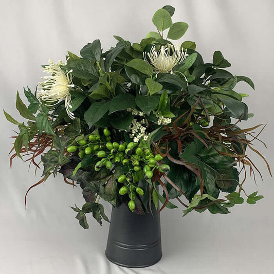 Cool rustic artificial flower arrangement of lush green foliage in a flat iron jug*, dotted with spider chrysanthemums. Ideal for a sideboard, hall table or conference room. Size: D50cm x H50cm . *The vase used for the arrangement may differ from the one depicted in the image.