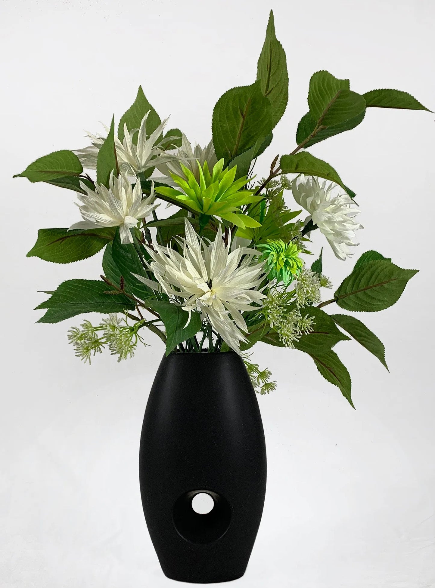 Verdant foliage contrasts with spider chrysanthemums to deliver a dramatic focus piece with bright green and ivory dahlias in a stylish black vase.  SIZE:  W50xH70cm  *Found Object – may not mean a new vessel/vase, but one which has been ‘found’ during our searches.  Please note: Sale price is for pictured item (Floor model) - ONE ONLY.