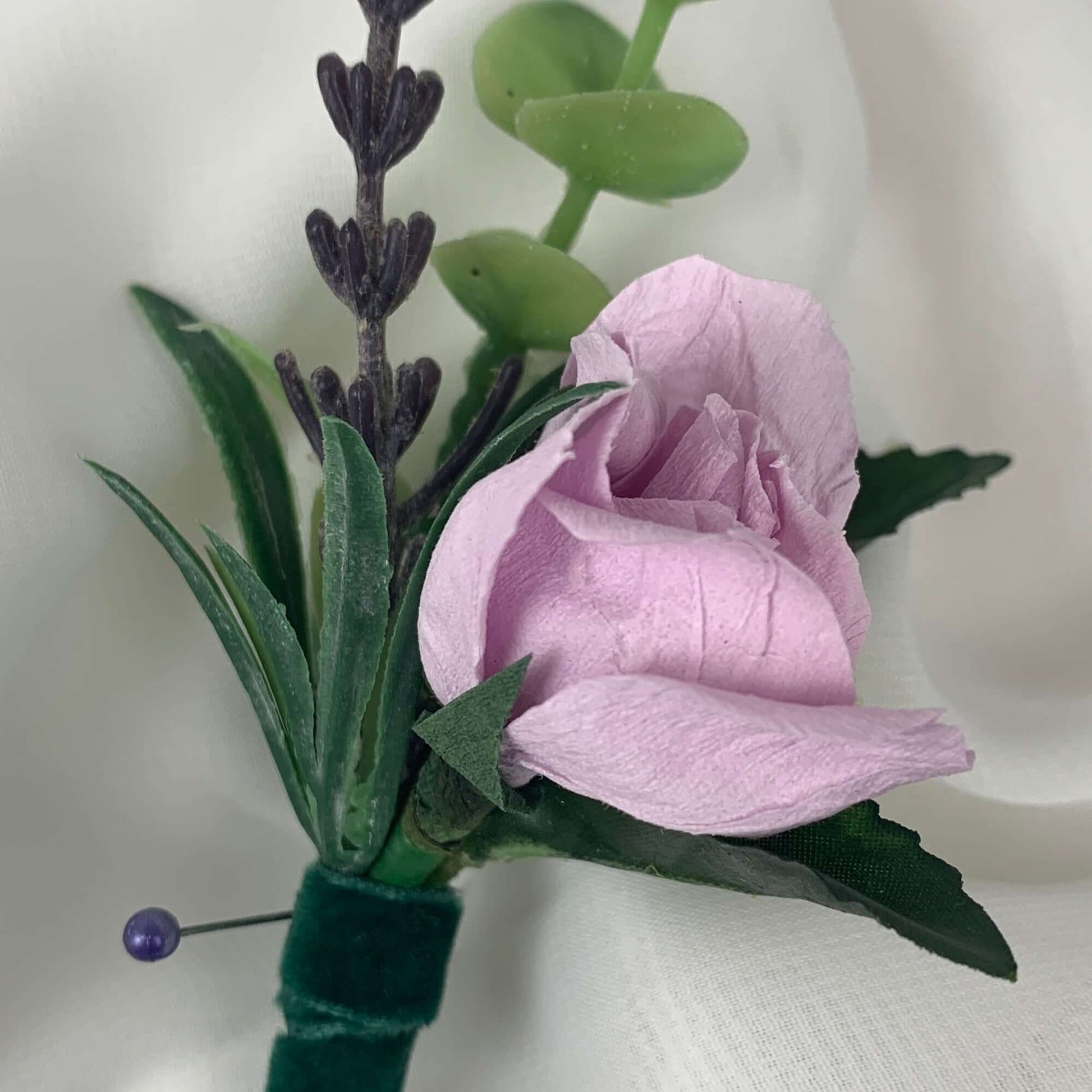A beautiful hand-crafted paper (faux) small lilac rose boutonnieres, with a green satin stem, mixed with artificial flowers and foliage, are made to order to match your wedding theme colour and are perfect for the groom, the groomsmen, and fathers for your special occasion. Atelier Blooms
