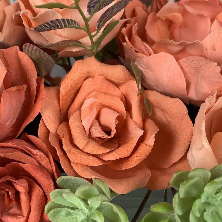 Exquisite Krosno trough* made of delicate glass, adorned with a stunning blend of burnished orange/peach handcrafted roses and peonies crafted from fine paper. Accompanied by autumnal faux foliage and sprays of succulents, this artificial arrangement crea