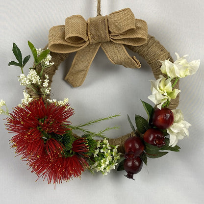 Our gorgeous Pomegranate and Pohutukawa Wreath is rich in colour and texture with white wax flowers, bougainvillea and foam berries. Bound in natural twine, a double hessian bow completes our wreath.  Size:  36cm outer/21cm inner diameter