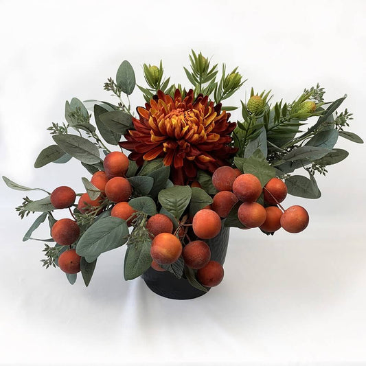 Gorgeous artificial flower arrangement with flaming shades of autumn, consists of a stunning artificial orange Winter Mum Chrysanthemum as the main piece, surrounded by Leucadendron Spray and melon berries in a black dimpled ceramic pot. The arrangement i
